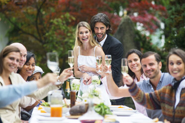 Braut und Bräutigam schneiden Hochzeitstorte auf einer Gartenparty an - ABF000600