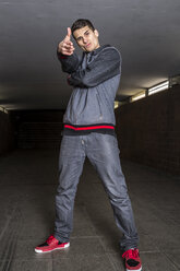 Germany, portrait of young break dancer in underpass making gun sign - STS000375