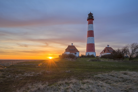 Deutschland, Schleswig-Holstein, Nordseeküste, Blick auf den Leuchtturm Westerheversand bei Sonnenuntergang, lizenzfreies Stockfoto