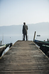 Mann steht auf Holzsteg und schaut auf den See - PA000576
