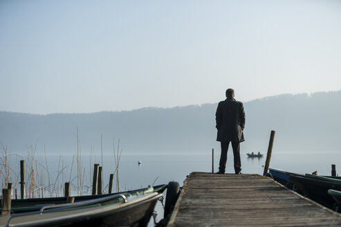 Mann steht auf Holzsteg und schaut auf den See - PA000578