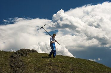 Austria, Radstadt, farmer on field, upcoming thunderstorm in the background - HHF004782