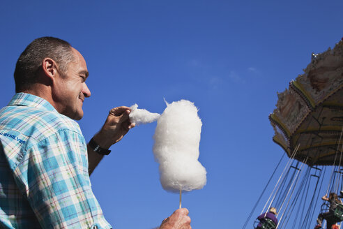 Mann genießt Zuckerwatte auf dem Jahrmarkt - GW002694