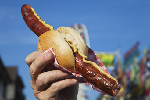 Mann hält Wurst mit Brötchen in der Hand - GWF002695