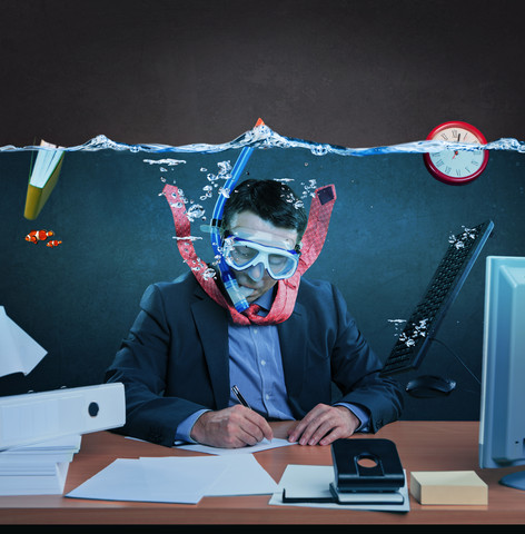 Büroangestellter mit Schnorchel, der unter Wasser arbeitet, lizenzfreies Stockfoto