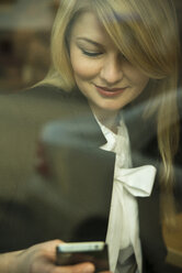 Germany, Mannheim, Young businesswoman in coffee shop, checking mobile phone - UUF000017