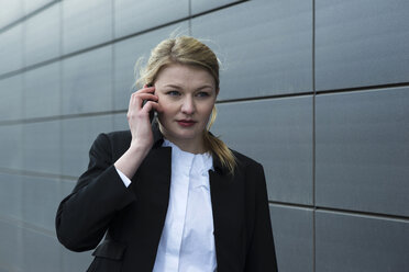 Germany, Mannheim, Young businesswoman using mobile phone - UUF000011