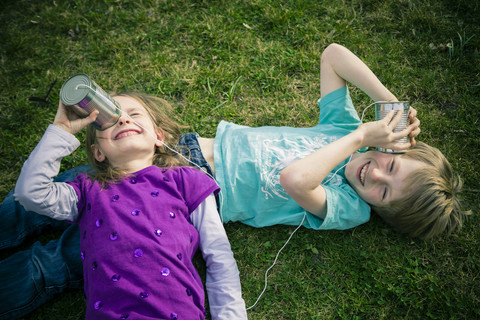 Boy and girl having fun with tin can phone stock photo