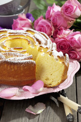 Geburtstagskuchen auf Kuchenstand und Rosen im Hintergrund - CSF021159