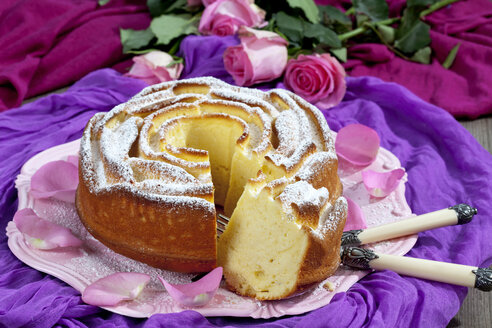 Geburtstagskuchen auf Kuchenständer und lila Tuch, Rosen im Hintergrund - CSF021127