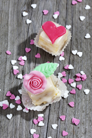 Zwei Petit Four und Backdekor auf grauem Holz, lizenzfreies Stockfoto