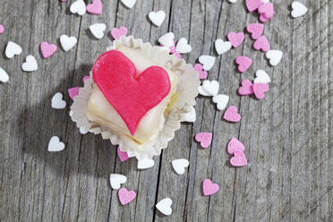 Petit four decorated with heart of marzipan on grey wood - CSF021128