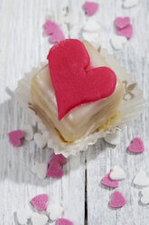 Petit four decorated with heart of marzipan on white wood - CSF021156