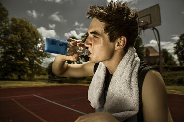 Porträt eines jungen Basketballspielers, der Wasser aus einer Flasche trinkt - GCF000016