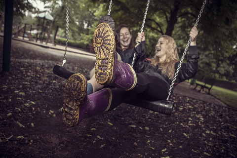 Zwei verspielte junge Frauen auf einer Schaukel, lizenzfreies Stockfoto