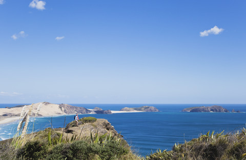 Neuseeland, Northland, Cape Reinga-Gebiet, Frau mit Blick auf Neuseelands Top End und die Tasmanische See, Cape Maria van Diemen, lizenzfreies Stockfoto