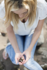 Young woman with shells in her hands sitting on the beach - LFOF000148