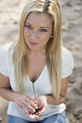 Porträt einer jungen Frau am Strand, die Muscheln in den Händen hält - LFOF000149