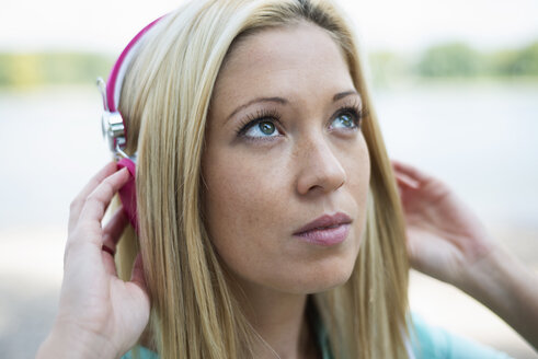 Porträt einer jungen Frau mit Kopfhörern, die nach oben schaut - LFOF000153