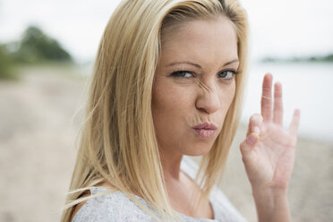 Portrait of young blond woman pouting mouth and showing ok sign - LFOF000162