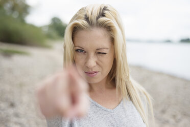 Porträt einer jungen blonden Frau, die auf den Betrachter zeigt - LFOF000164