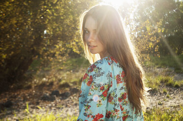 Portrait of female teenager viewing over her shoulder at backlight - LFOF000176