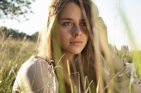 Porträt eines träumenden weiblichen Teenagers, der auf einer Wiese sitzt, lizenzfreies Stockfoto