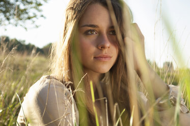 Portrait of daydreaming female teenager sitting on a meadow - LFOF000179