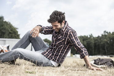 Smiling man sitting on grass - MUMF000046