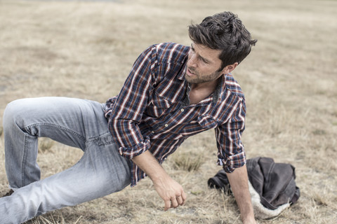 Serious looking man placing on grass stock photo