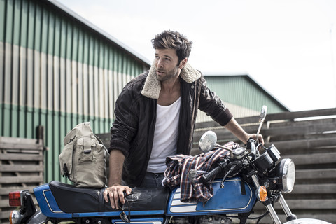 Porträt eines Mannes, der sich auf ein Motorrad stützt, lizenzfreies Stockfoto
