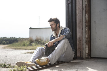 Man sitting on ground watching something - MUMF000026