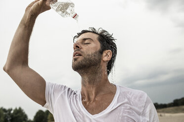 Porträt eines Mannes, der Wasser aus einer Flasche über sich gießt - MUMF000027