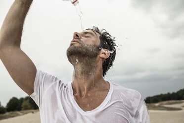 Porträt eines Mannes, der Wasser aus einer Flasche über sich gießt - MUMF000048