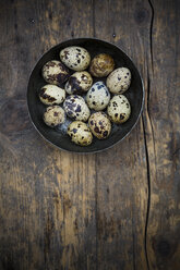 Bowl of quail eggs on dark wooden table, elevated view - LVF000965