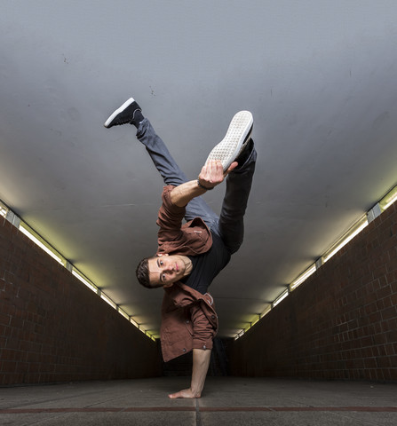 Junger Breakdancer macht einen Handstand in einer Unterführung, lizenzfreies Stockfoto