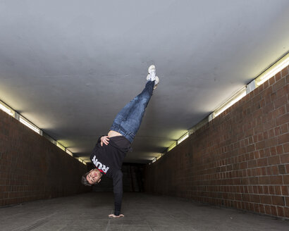 Junger Breakdancer macht einen Handstand in einer Unterführung - STSF000398