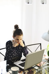 Junge Frau bei der Arbeit mit Laptop zu Hause - EBSF000150