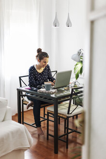 Junge Frau bei der Arbeit mit Laptop zu Hause - EBSF000122