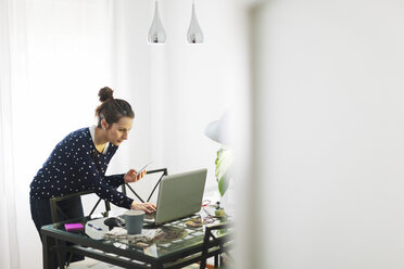 Junge Frau bei der Arbeit mit Laptop zu Hause - EBSF000124