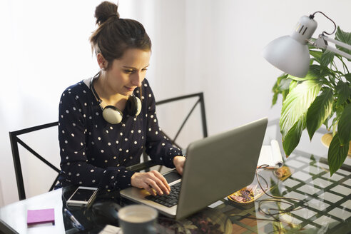 Junge Frau bei der Arbeit mit Laptop zu Hause - EBSF000152