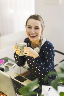 Junge Frau bei der Arbeit mit Laptop zu Hause - EBSF000133