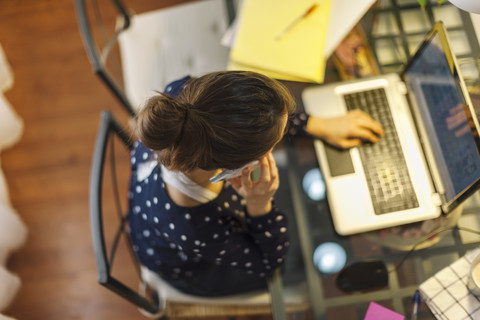 Junge Frau bei der Arbeit mit Laptop zu Hause, lizenzfreies Stockfoto