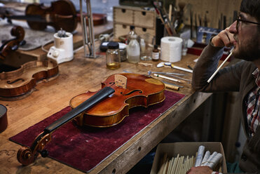 Violin maker at workbench in his workshop - DIKF000095