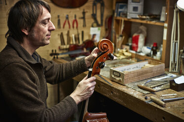 Violin maker in his workshop adjusting a cello mechanism - DIKF000105