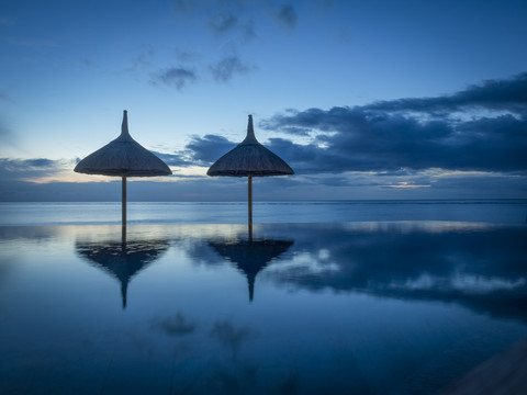 Mauritius, La Preneuse, zwei Sonnenschirme am Schwimmbad vor dem Meer, lizenzfreies Stockfoto