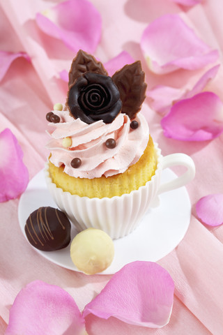 Backform in Form einer Tasse mit dekoriertem Cupcake auf rosa Krepppapier, lizenzfreies Stockfoto