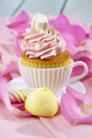 Backform in Form einer Tasse mit dekoriertem Cupcake auf rosa Krepppapier, lizenzfreies Stockfoto