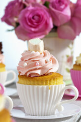 Backform in Form einer Tasse mit dekorierten Cupcakes vor rosa Rosen - CSF021178