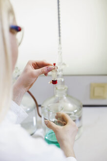 Female scientist filling liquid in test tube - NAF000003
